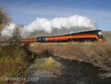 A colorful autumn scene of a steam engine thundering through Montana